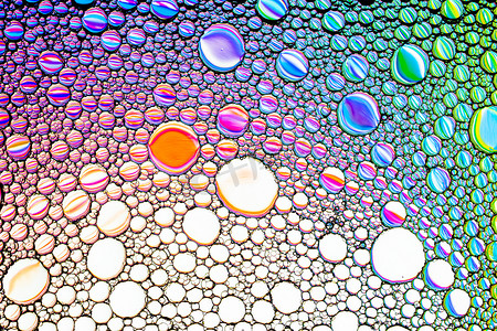 椭圆形不规则图形摄影照片_水面上有五颜六色的油滴。