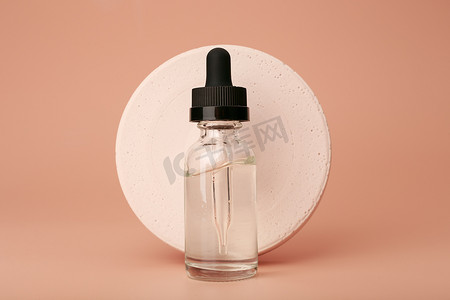 米色背景下圆形石膏圆透明玻璃瓶中的皮肤血清或油