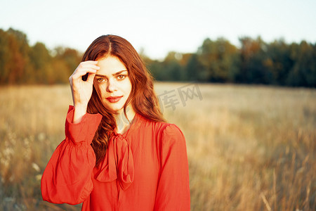 红发摄影照片_野外自然夏季穿着红色裙子的可爱红发女人