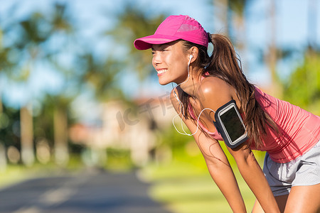 快乐的夏季跑步女跑步者在城市街道上用手机运动臂章和耳机听音乐，积极的生活方式。