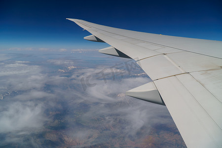 航空机翼摄影照片_飞行和旅行，在阴天从机翼上的飞机窗户观看。