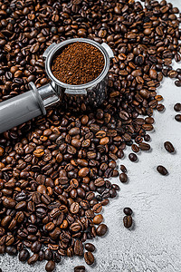 咖啡机和咖啡豆摄影照片_在 Portafilter 中研磨咖啡，用于浓缩咖啡和咖啡豆。