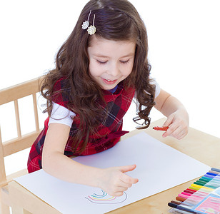 小女孩坐在桌边用彩色铅笔画画