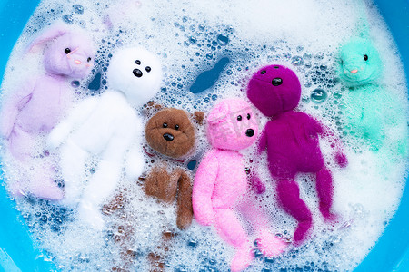 将兔子娃娃和小熊玩具浸泡在洗衣粉水里
