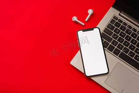 iphone表盘摄影照片_俄罗斯图拉 — 2019 年 5 月 24 日：红色背景中的苹果 iphone X 和 Airpods，带笔记本。