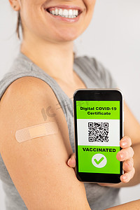 接种疫苗后肩上贴着膏药的妇女在智能手机上展示二维码。