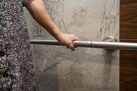 亚洲老年或老年老妇人病人在护理医院病房使用厕所浴室手柄安全，健康强大的医疗理念。