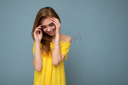 年轻美丽的深色金发女郎带着真挚的情感被隔离在背景墙上，复制空间穿着时尚的夏季黄色连衣裙。