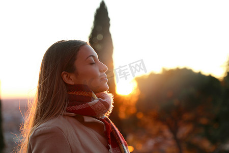 日落时穿着夹克呼吸新鲜空气的女孩的肖像