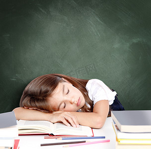 疲惫的小女孩睡在学校的课桌上。