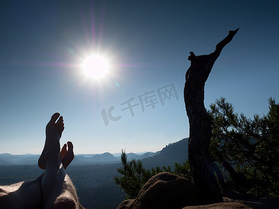 无风摄影照片_疲惫出汗的双腿在断松树的岩石顶上。