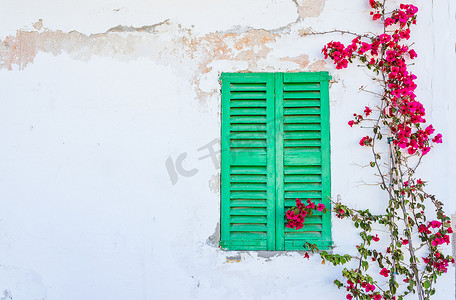有绿色窗口和九重葛花的地中海房子墙壁