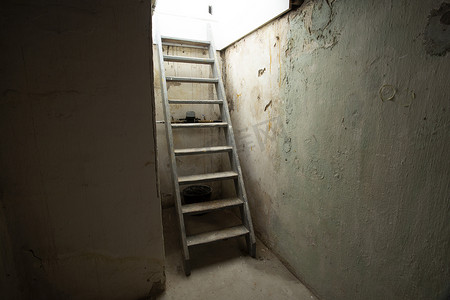 在黑暗的地下室，旧废弃建筑中，地窖木楼梯通向石头和砖块的低层