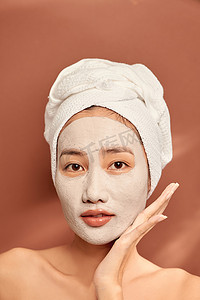 清洁面膜摄影照片_头上戴着毛巾的快乐女人在脸上涂上清洁面膜