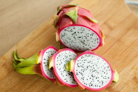 厨房木板上的火龙果或火龙果片，有粉红色的皮肤和白色的果肉，有黑色的种子。