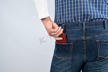 穿着蓝色牛仔裤和格子衬衫的男人推着棕色皮革钱包