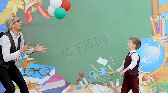 父亲在第一个学习日在学校背景上玩儿子气球
