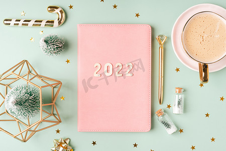 顶部视图桌面圣诞粉红色记事本，带有 2022 个字母文本。