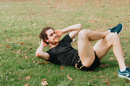 一个年轻人在公园草地上训练做仰卧起坐的特写