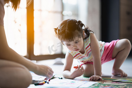 可爱的小女孩和她妈妈在家里画画
