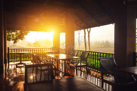 室内避雨室外打闪摄影照片_餐厅厨房室内概念：晚上夕阳下的空户外餐桌，有自然景观背景