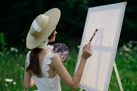 穿白裙的女人在自然画架上画一幅画