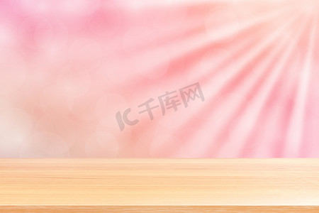 蓝色渐变背景摄影照片_空木桌地板上柔和的粉红色散景灯光束闪耀渐变背景，木板空在粉红色散景彩色灯光上，粉红色彩色散景灯渐变软用于横幅广告