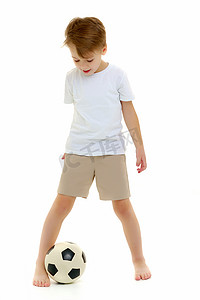 一个穿着纯白T恤的小男孩正在玩足球