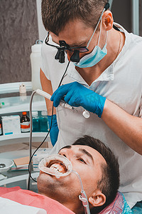 唾液的奥秘摄影照片_牙医的程序，牙医准备病人和工具，以去除病人嘴里的牙垢、唾液喷射器和牵引器。