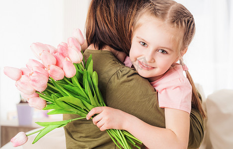 母亲孩子拥抱摄影照片_孩子拥抱母亲，手捧鲜花
