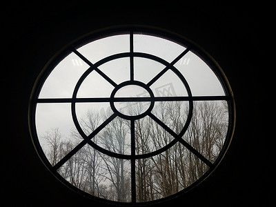 圆形窗格摄影照片_有树和树枝的圆形玻璃窗