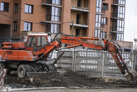 橙色挖掘机在建筑工地上用砾石工作，并将其从一个地方运到另一个地方。