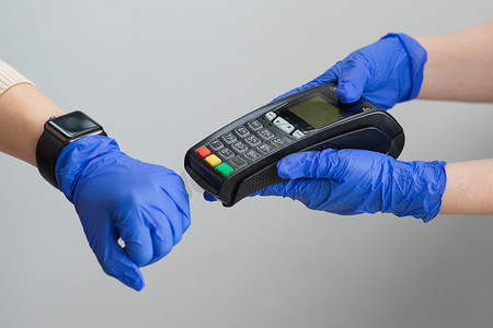 女人手戴手套，使用智能手表在零售店的销售点终端购买产品，并使用 nfc 识别支付技术进行验证。