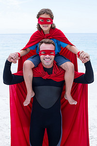 穿着超级英雄服装的快乐父亲肩上扛着儿子