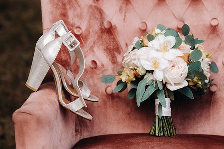 胸花新娘摄影照片_椅子上放着牡丹和玫瑰的婚礼花束，还有胸花。婚礼上的装饰