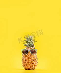 创意菠萝用太阳镜和黄色背景中的贝壳抬头，暑假海滩创意设计模式，复制空间特写
