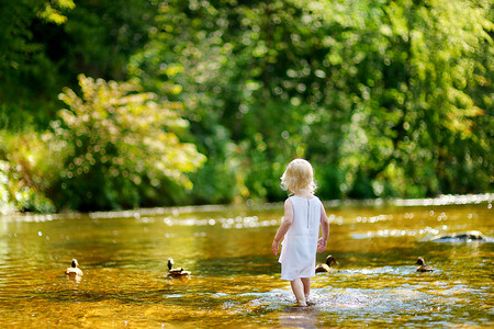 可爱的幼儿女孩在河边玩耍