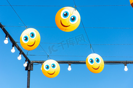 表情人物摄影照片_在蓝天上悬挂快乐的表情符号或表情符号，庆祝街头节日
