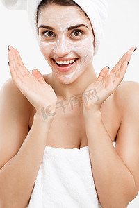 美白面膜背景摄影照片_美容护肤概念-美丽的白种女人面部肖像在她的面部皮肤白色背景上应用奶油面膜。