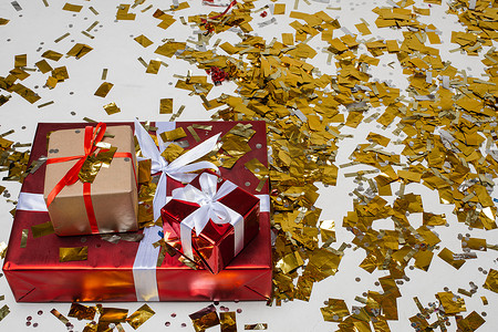 地板上的三件礼物覆盖着金色的五彩纸屑。