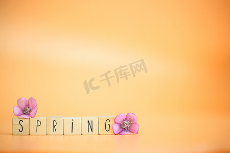 明亮柔和的橙色背景上的春天文字，色彩缤纷的花朵，快乐的春天，贺卡，带复制空间的季节概念，复古的现代设计