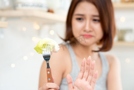 限制饮食摄影照片_厌倦了饮食限制的年轻女性决定是否在家吃健康食品