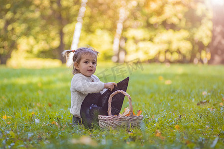 在秋天阳光明媚的公园里玩女巫帽的蹒跚学步。