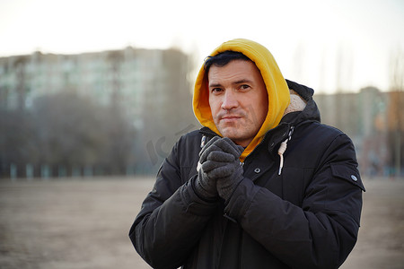 人冻摄影照片_黄色敞篷和黑色夹克的年轻冷冻人。