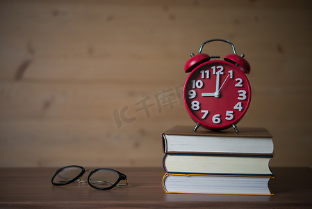 早上 9 点的闹钟，在木桌上戴着眼镜的一摞书上