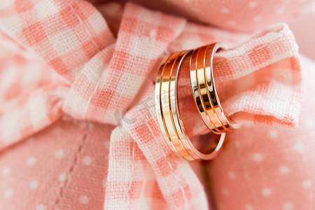 粉红色格子织物上的金色结婚戒指。