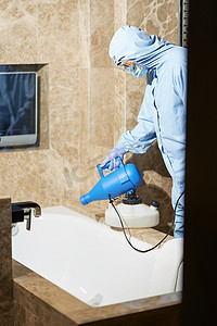 身着防护服和眼镜的技术人员对酒店浴室进行消毒