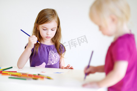 两个小姐妹用彩色铅笔画画