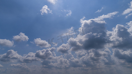 蓝色天空的云摄影照片_明亮的蓝色天空中漂浮着白色和黑色的云