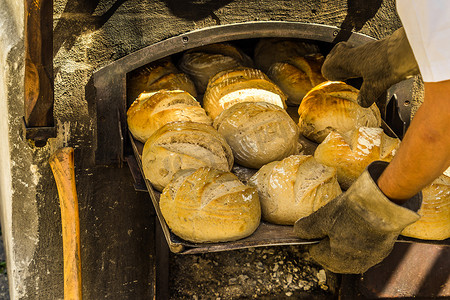 面包销售摄影照片_在带木柴的烤箱的烤盘上新鲜出炉的面包